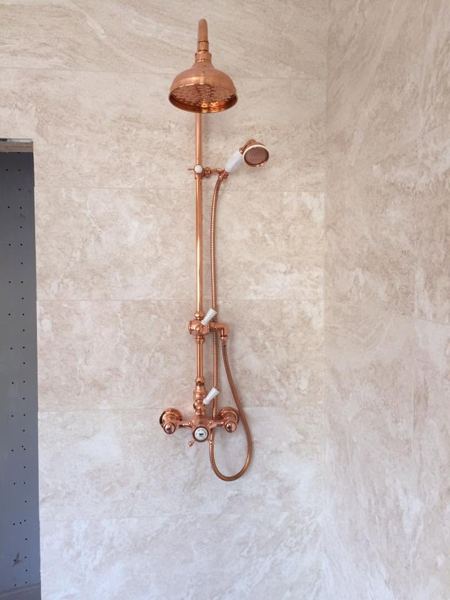 Copper exposed shower on a marble-effect wall