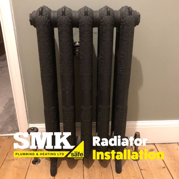 Ornate cast-iron radiator on floorboards